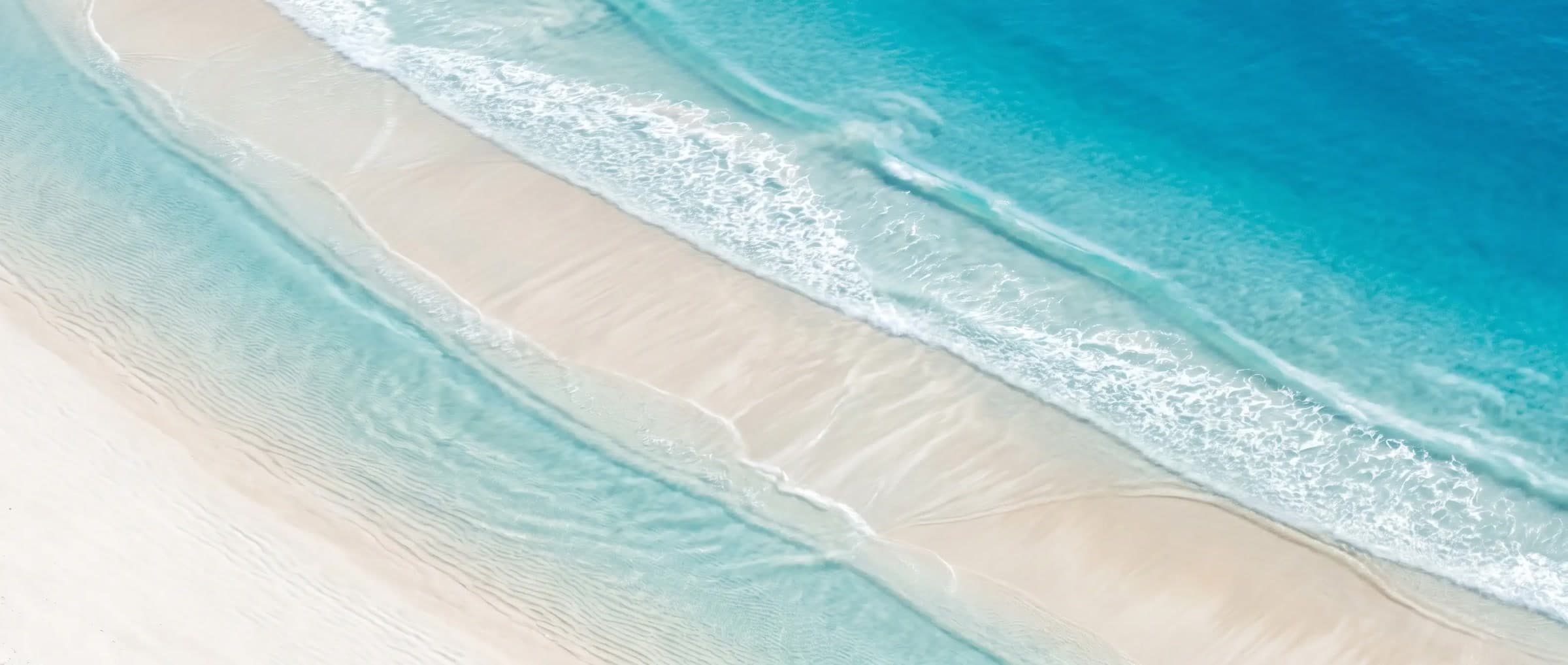 Ribbons of turquoise water sweeping over white sand, seen from above